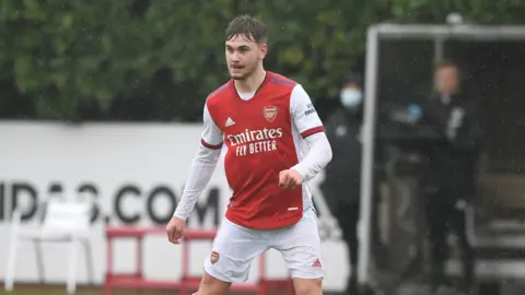 Billy Vigar playing for Arsenal, in the club's home colours of red and white.