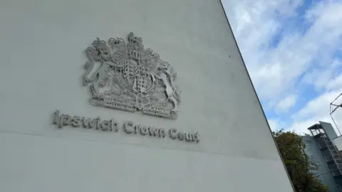 The outside of Ipswich Crown Court, on the wall is a large logo with Ipswich Crown Court written. 