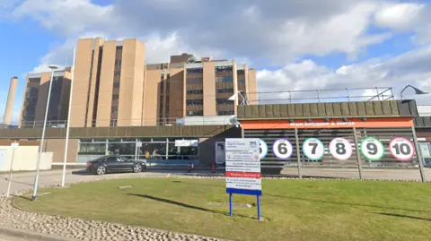 Google The front entrance to Raigmore Hospital with signs showing numbers and colours of different zones inside the large building.